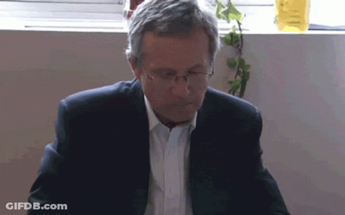 Man In Glasses And Suit Looking Down GIF