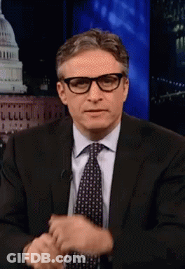 Man In Glasses And Suit Sitting In Front Of Building GIF