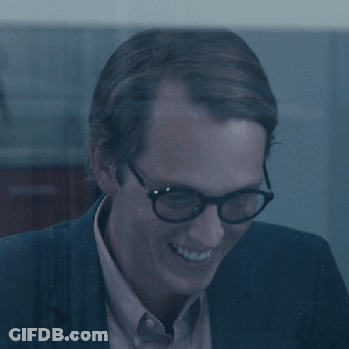 Man In Glasses And Suit Smiling In Dark Room GIF