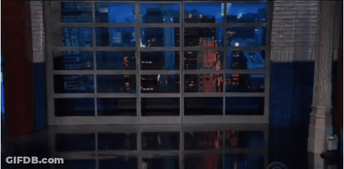 Man In Glasses And Suit Standing In Front Of Window GIF