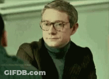 Man In Glasses And Turtleneck Talking To Another Man GIF
