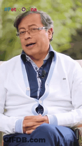 Man In Glasses And White Sweater Sitting By Petroopina Sign GIF