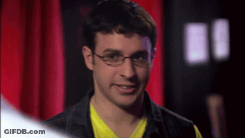Man In Glasses And Yellow Smiling Before Red Curtain GIF