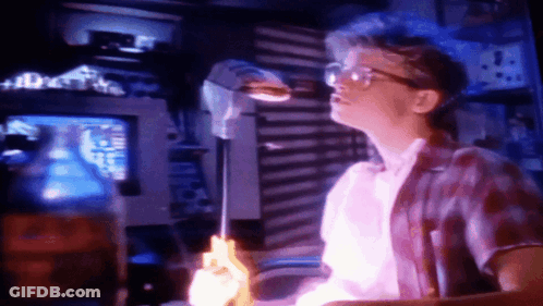 Man In Glasses Holding Purple Object At Computer GIF