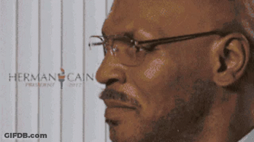 Man In Glasses In Front Of Herman Cain Poster GIF