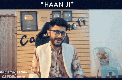 Man In Glasses Sitting In Front Of Wall Saying Co GIF