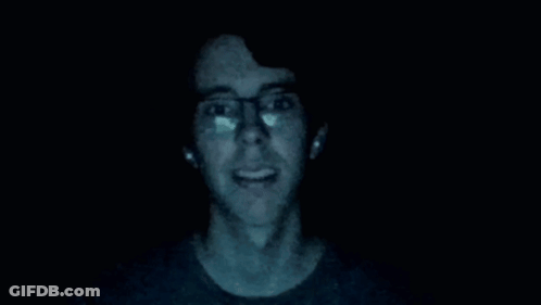 Man In Glasses Standing In Dark With Hands Up GIF