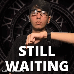 Man In Glasses Standing In Front Of Clock Saying Still Waiting GIF