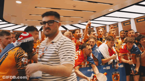 Man In Glasses Surrounded By Soccer Players And Fans GIF