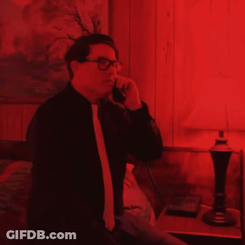 Man In Glasses Talking On Cell Phone In Red Room GIF