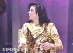 Man In Gold Dress Holding Trophy On Stage GIF
