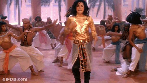 Man In Gold Outfit Stands In Front Of Group GIF