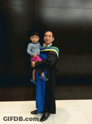 Man In Graduation Gown Holding Baby GIF