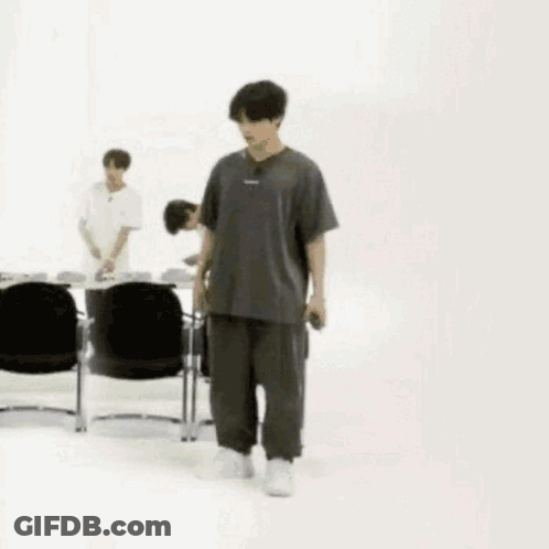 Man In Gray And Black Walking Past Chairs GIF