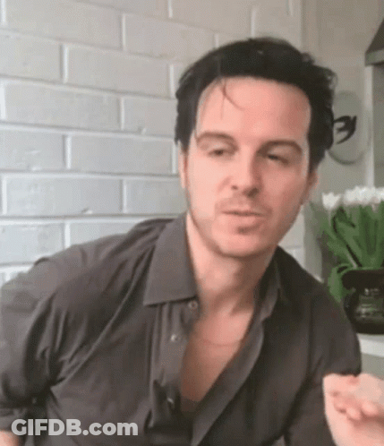 Man In Gray Shirt Making Funny Face At Brick Wall GIF