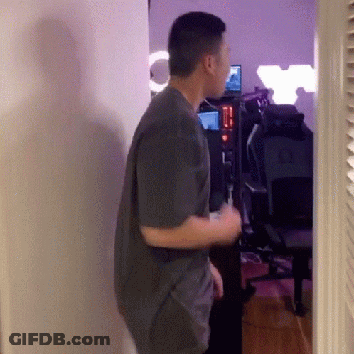 Man In Gray Shirt Standing In Room With Chair And Computer GIF