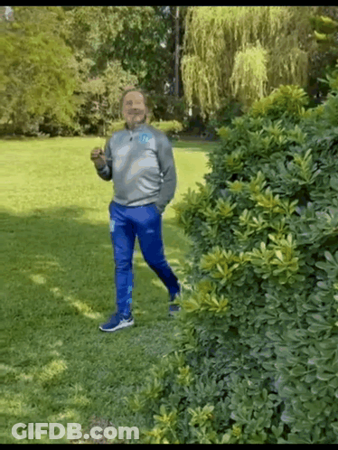 Man In Gray Sweatshirt And Blue Pants Standing In Park GIF
