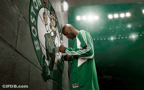 Man In Green Adidas Jacket In Front Of Boston Celtics Logo GIF