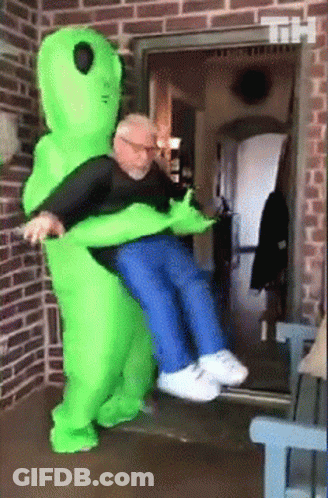 Man In Green Alien Costume Holding Another Man GIF