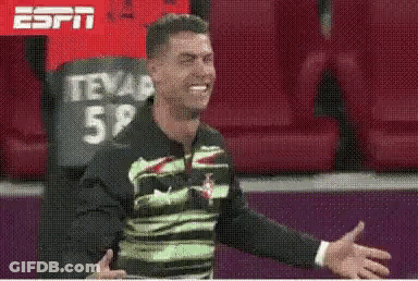 Man In Green And Black Shirt Smiling In Stadium GIF