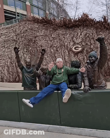 Man In Green Bay Packers Sweatshirt Sitting On Ledge GIF
