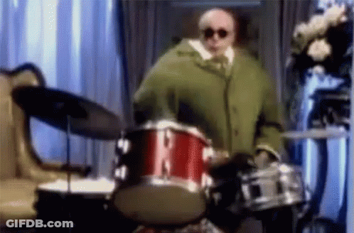 Man In Green Coat Playing Drum Set GIF