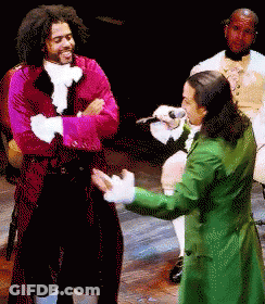 Man In Green Coat Singing Into Microphone With Man In Red Coat GIF