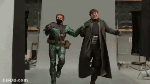 Man In Green Costume And Man In Black Coat Dancing GIF