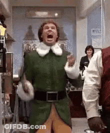 Man In Green Elf Costume Standing In Hallway GIF