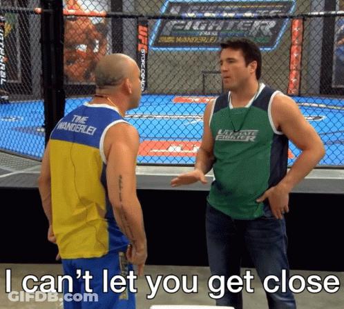 Man In Green Fighter Shirt Talking To Tank Top Man GIF