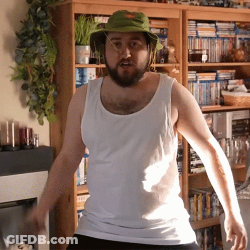 Man In Green Hat And White Tank Top By Bookshelf GIF