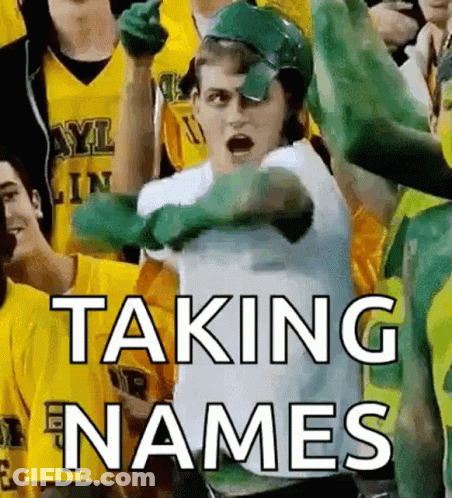 Man In Green Helmet Taking Names In Front Of Crowd GIF