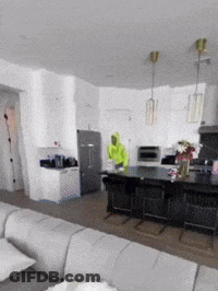 Man In Green Hoodie In Living Room And Kitchen GIF