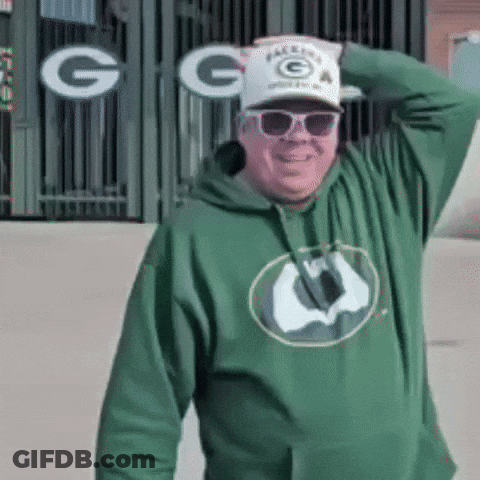 Man In Green Hoodie Sunglasses And Hat In Front Of Green Bay Packers Sign GIF