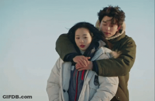 Man In Green Jacket Hugging Woman In White Parka GIF