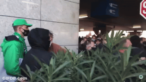 Man In Green Jacket In Front Of Crowd GIF