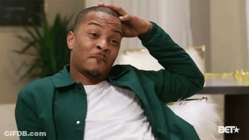 Man In Green Jacket Scratching Head On Couch GIF