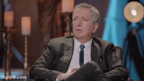 Man In Green Jacket Sitting With Hats Off To You Sign GIF