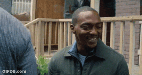 Man In Green Jacket Smiling Beside Wooden Fence GIF