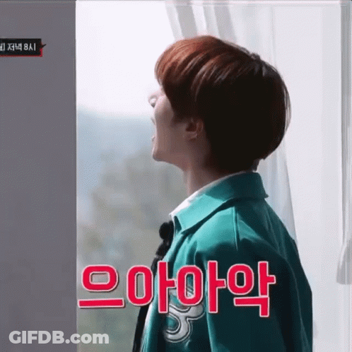 Man In Green Jacket Standing In Front Of Window With Korean Writing GIF