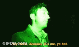 Man In Green Jacket Talking In Dark Room GIF
