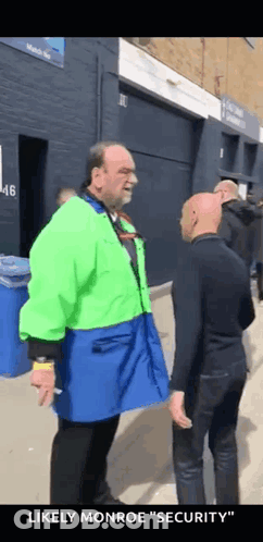 Man In Green Jacket Talking To Another Man GIF