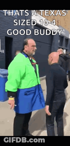 Man In Green Jacket Talking To Man In Blue Apron GIF
