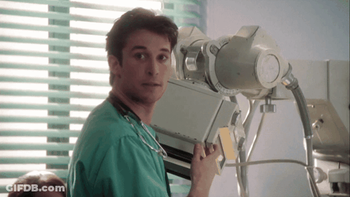 Man In Green Scrub Holding X-Ray Machine In Front Of Window GIF