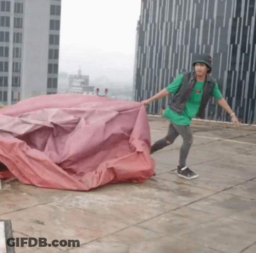 Man In Green Shirt And Black Hat Holding Red Tarp GIF