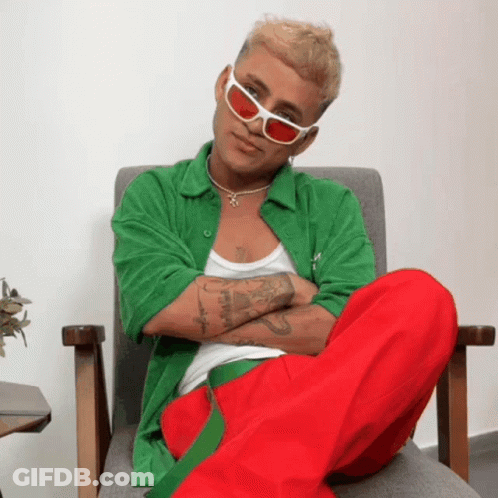 Man In Green Shirt And Red Pants Sitting With Arms Crossed GIF
