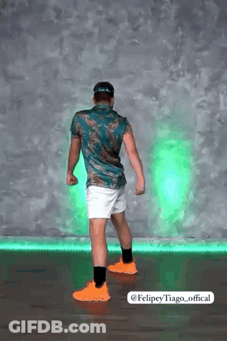 Man In Green Shirt And White Shorts In Front Of Green Light GIF