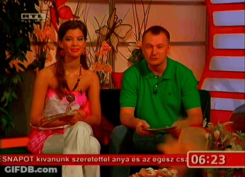 Man In Green Shirt And Woman In Pink Top In Front Of Screen Saying 06:23 GIF