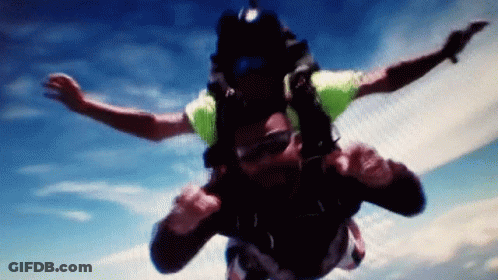Man In Green Shirt Flying Through Blue Sky GIF