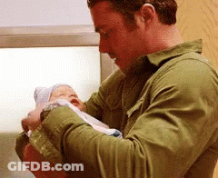 Man In Green Shirt Holding Newborn Baby GIF